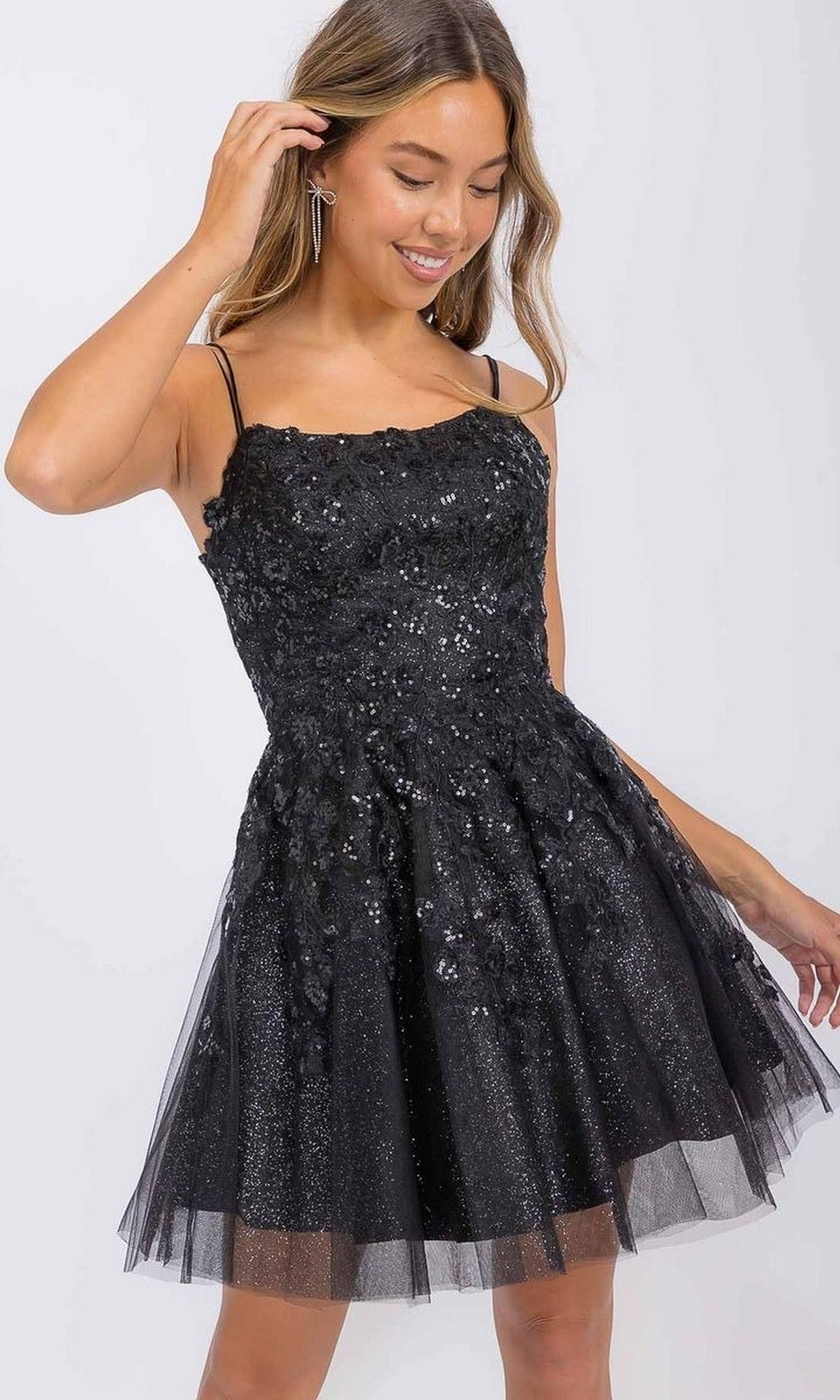 Woman wearing the Eureka EK127 short homecoming dress, featuring a sleeveless black sequin bodice, flared tulle skirt, and corset-style back, standing against a plain background.